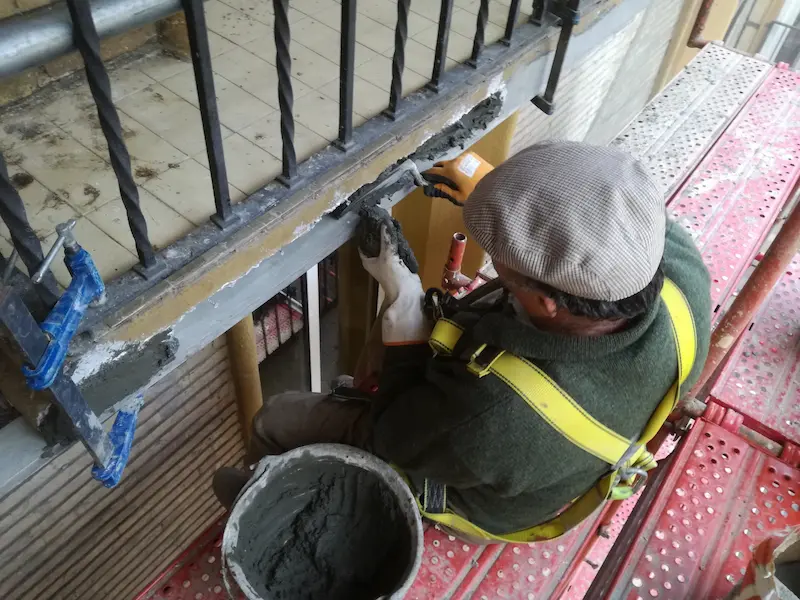 Albañil reparando el frente de un balcón en Zaragoza